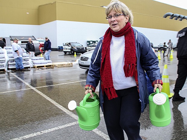 Cathy Mabe, moradora de Spring Hill, South Charleston, em West Virginia, usa dois regadores para transportar água neste sábado (11) (Foto: Lisa Hechesky/Reuters)